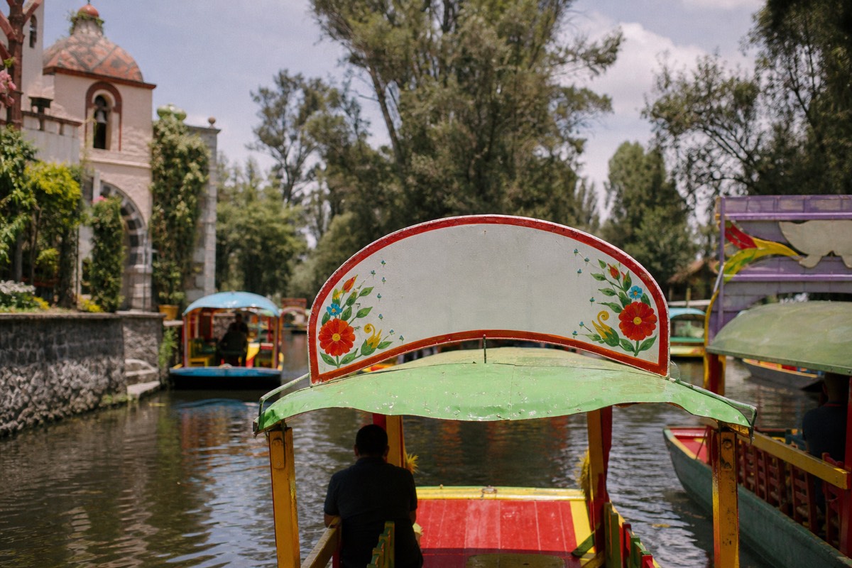 Trajinera on the Xochimilco canals with colonial Coyoacán architecture suggested in a full-day tour collage scene