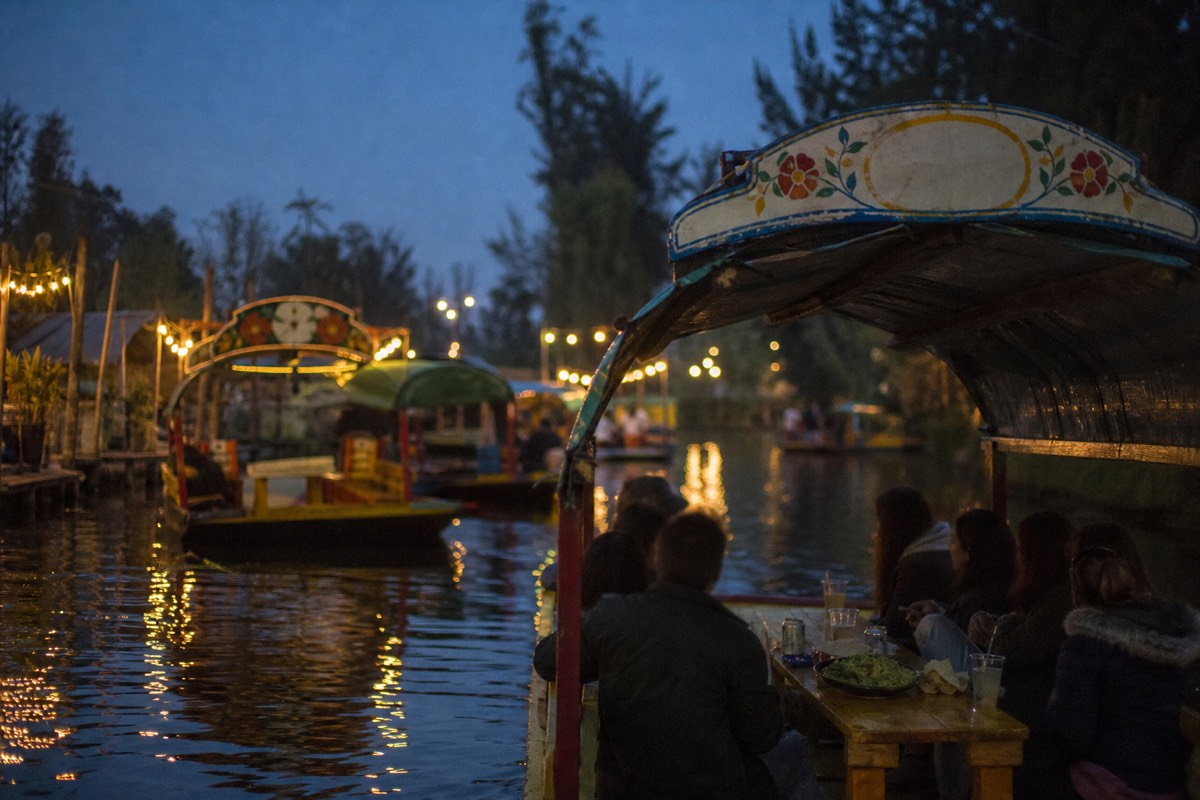 Shared trajinera full of travellers with drinks and guacamole cruising the Nativitas canals of Xochimilco