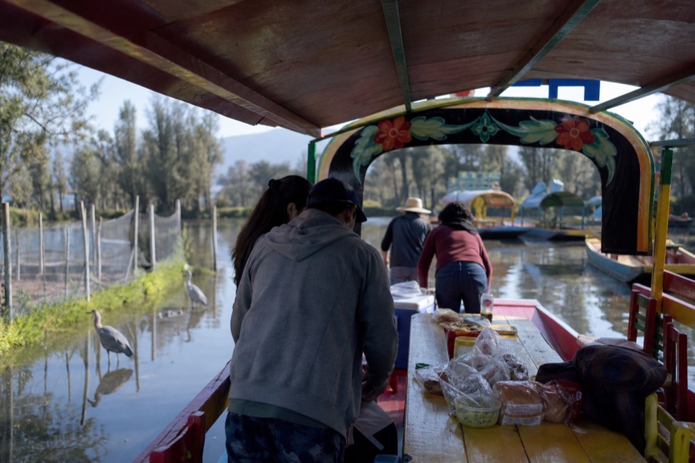 A group unpacking coolers and snacks onto the long wooden table of a rented canal boat