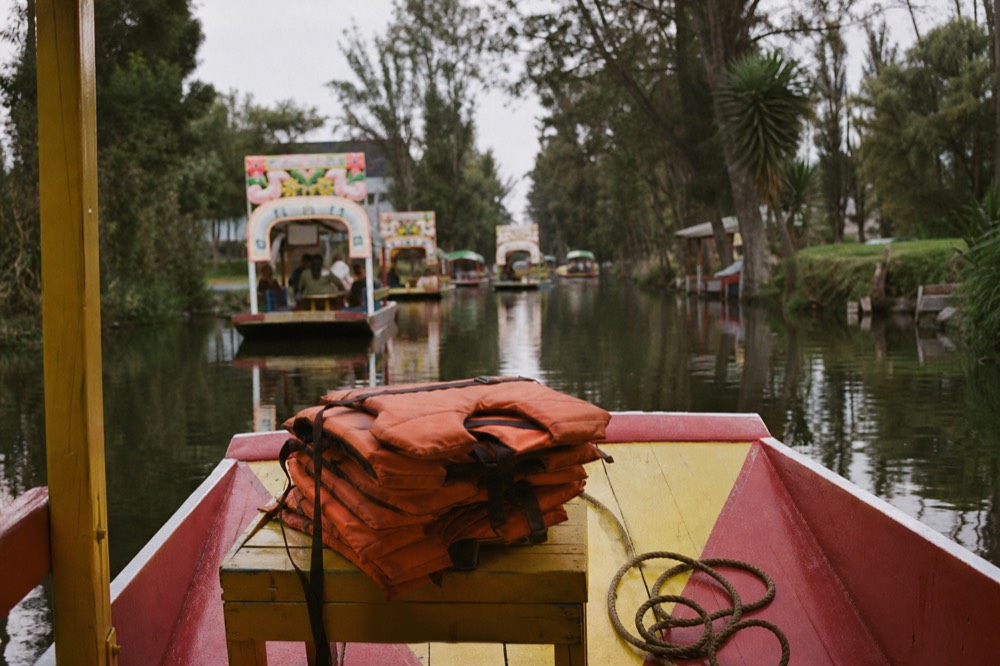 Orange life jackets stacked on a bench at the front of a canal boat beside a coiled mooring rope